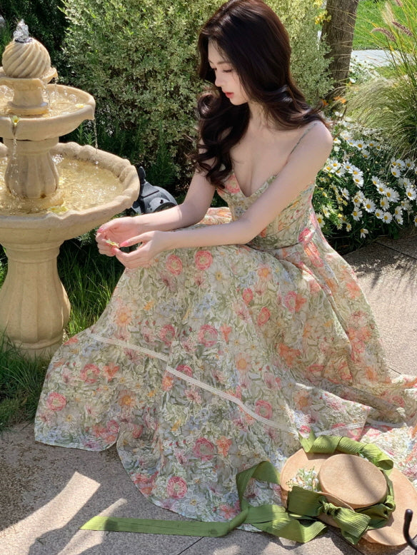 Floral print spaghetti strap maxi dress styled in a garden beside a fountain, romantic spring summer dress