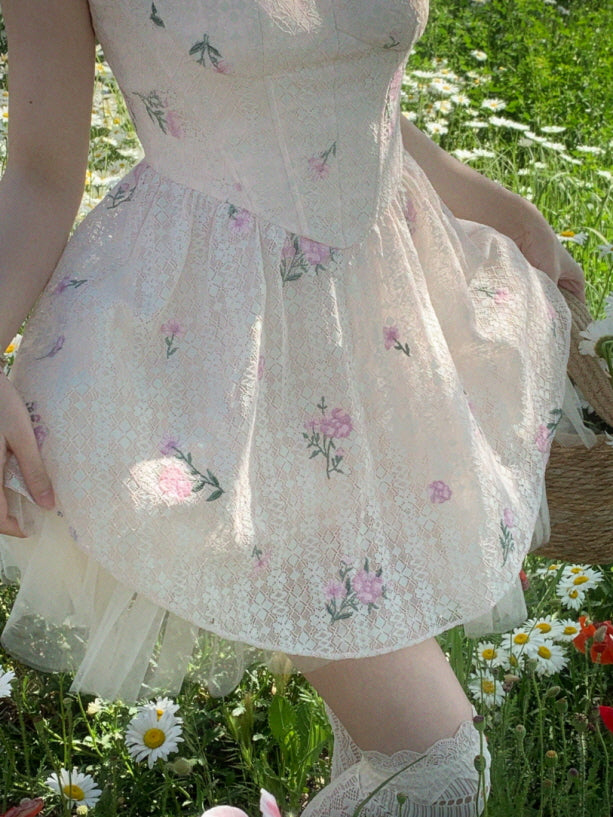 Close-up of a romantic ivory floral lace mini dress with pink flower embroidery and soft tulle hem in a daisy meadow