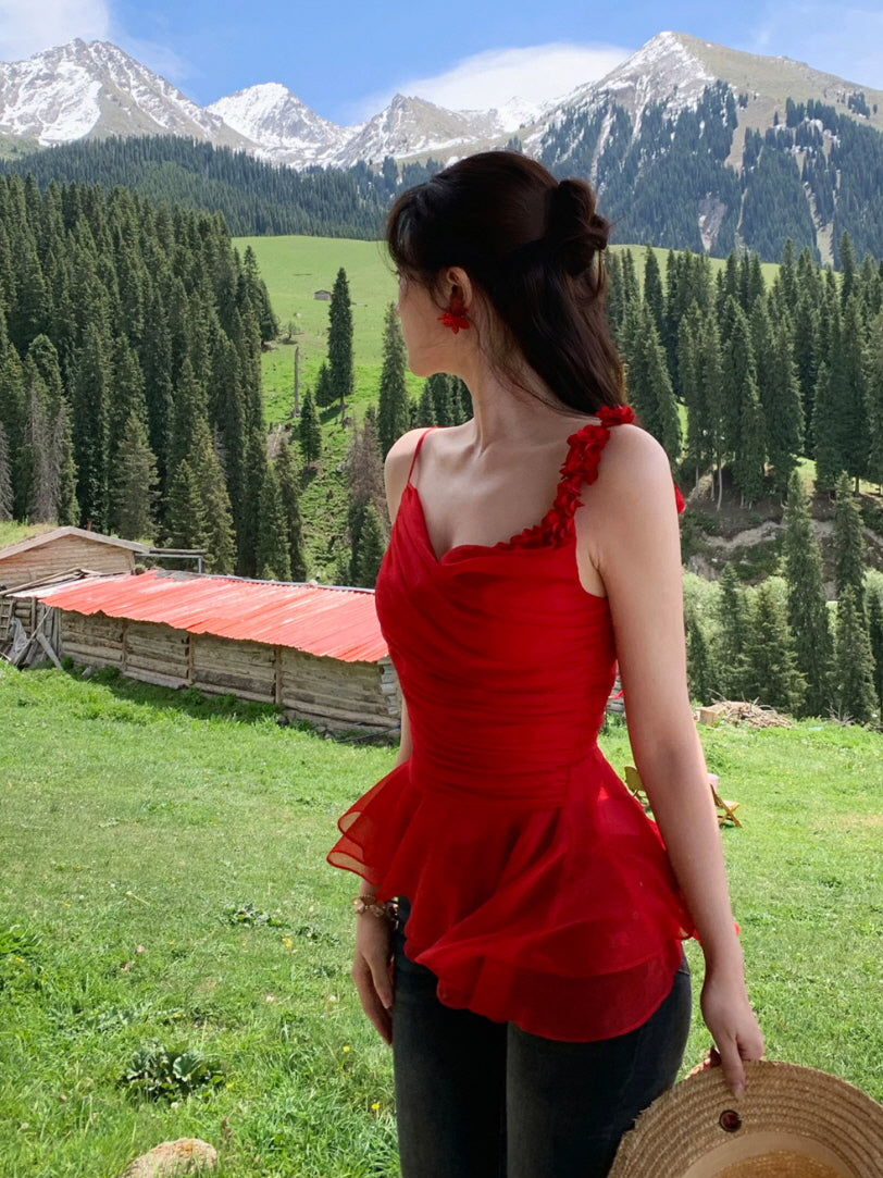 Red one-shoulder summer top with floral applique strap and peplum hem, worn with jeans in an alpine meadow