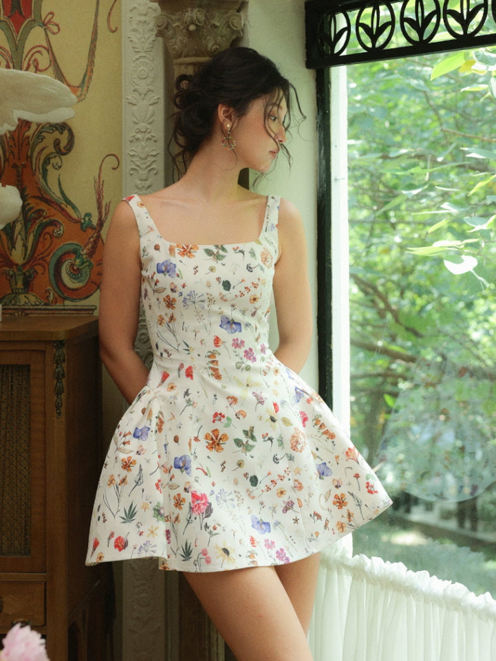 Cream floral fairycore mini dress with wide straps and fitted bodice, worn by a window in a cottagecore interior