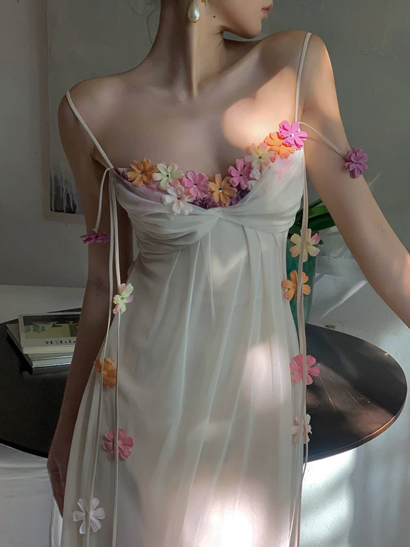 Close-up of ivory floral slip dress with colorful flower appliques and delicate ribbon details