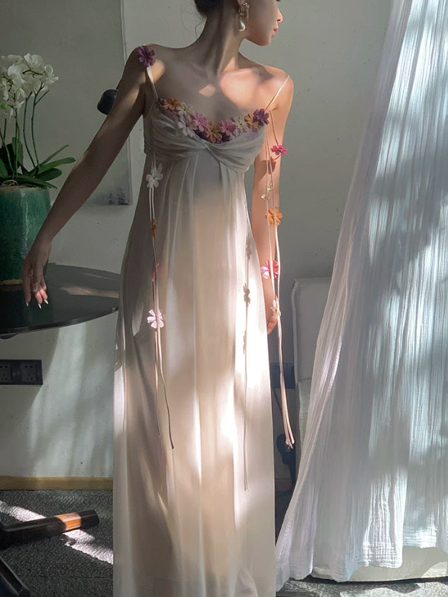 Ivory fairycore maxi dress with colorful floral appliques and delicate shoulder straps in soft sunlight
