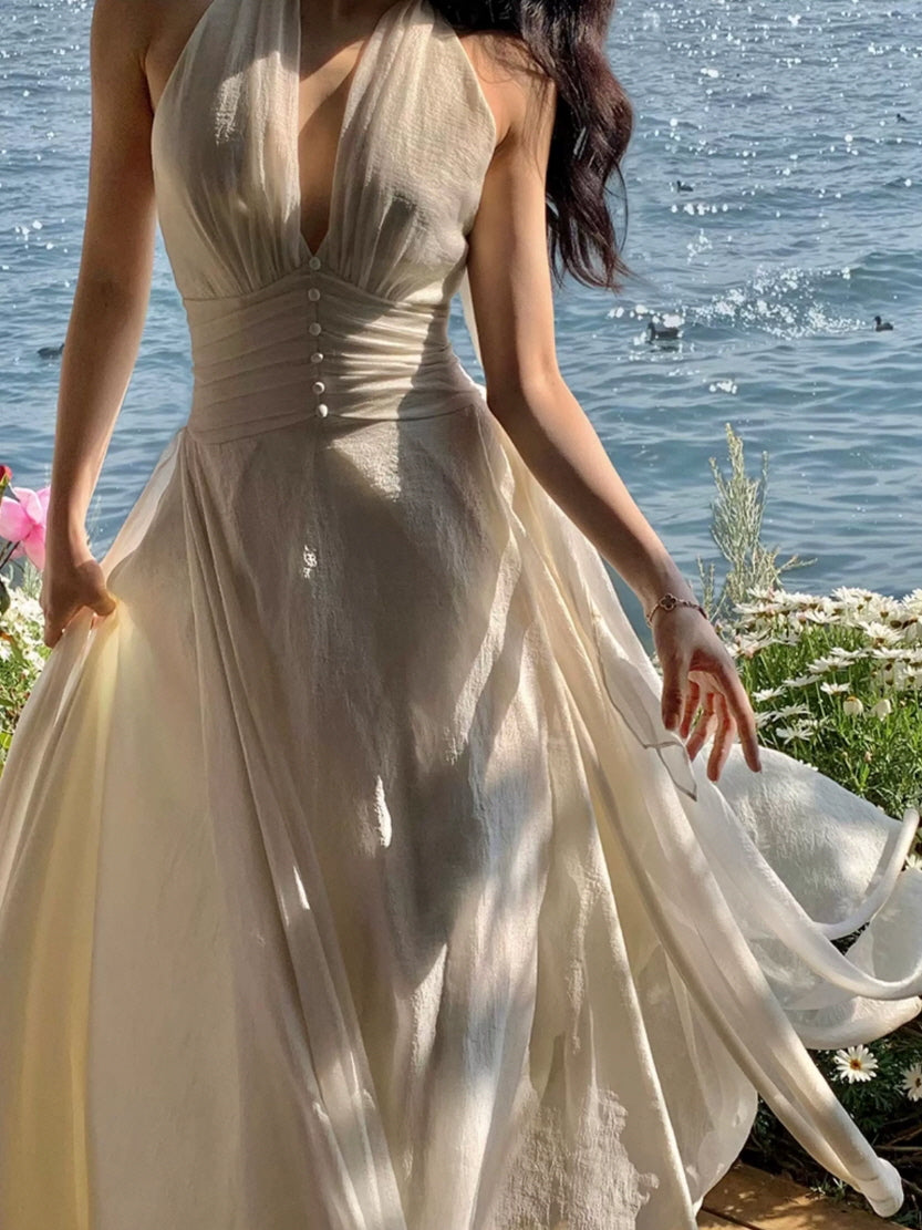 Close-up of ivory halter maxi fairycore dress with pearl button details and sheer flowing overlay