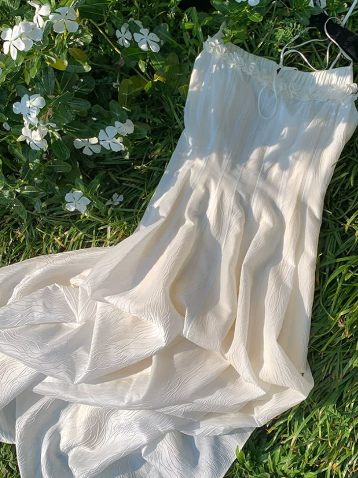 Ivory fairycore maxi dress with delicate spaghetti straps and floral trim on the grass