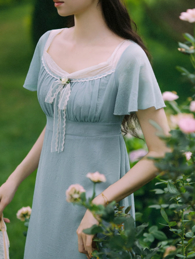 Close-up of vintage blue cottagecore dress with gathered bodice, lace trim, and ribbon bow
