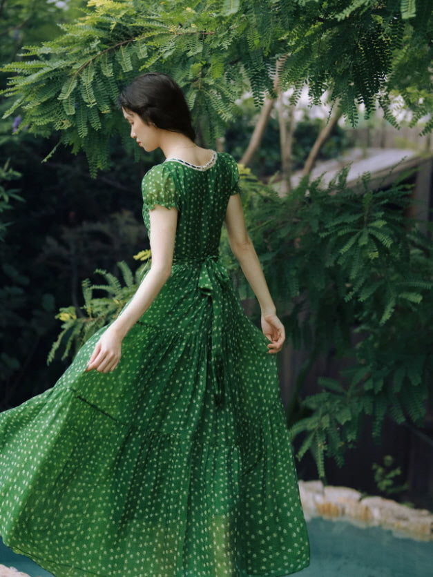 Back view of green floral maxi dress with waist tie and flowing tiered skirt