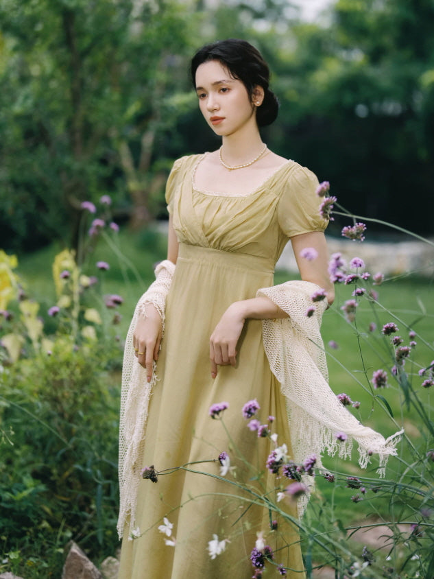 Elegant vintage cottagecore maxi dress with puff sleeves, ruched bodice and soft olive green fabric surrounded by wildflowers