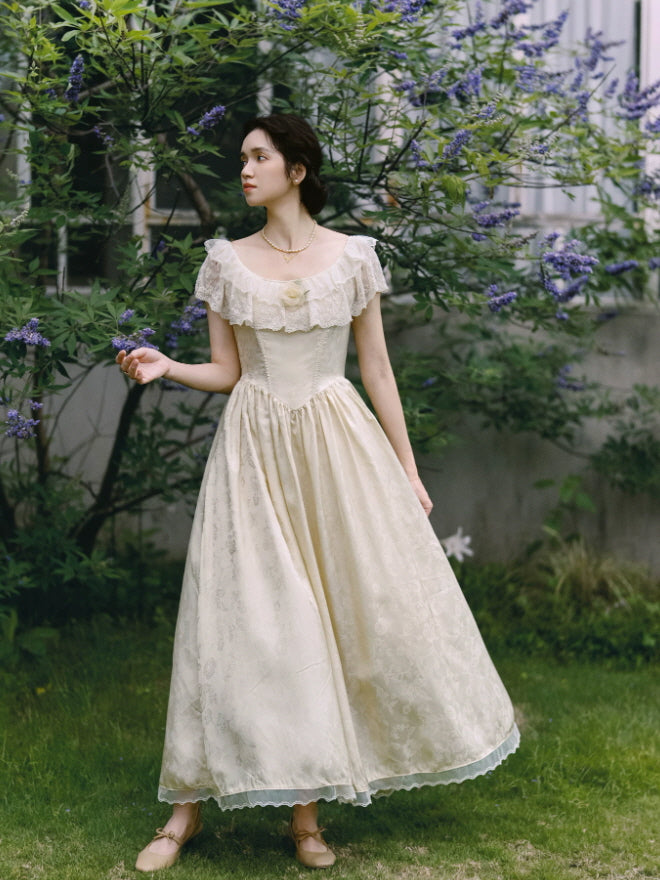 Ivory vintage cottagecore maxi dress with lace ruffle neckline, fitted bodice and flowing floral jacquard skirt in a garden