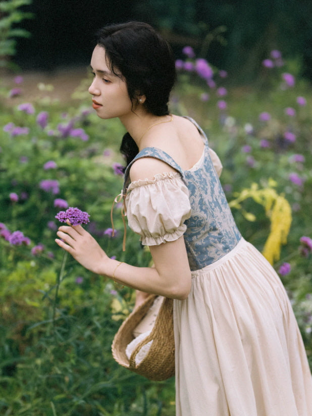Back view of a blue cottagecore dress with fitted corset bodice, puff sleeves and long flowing prairie skirt
