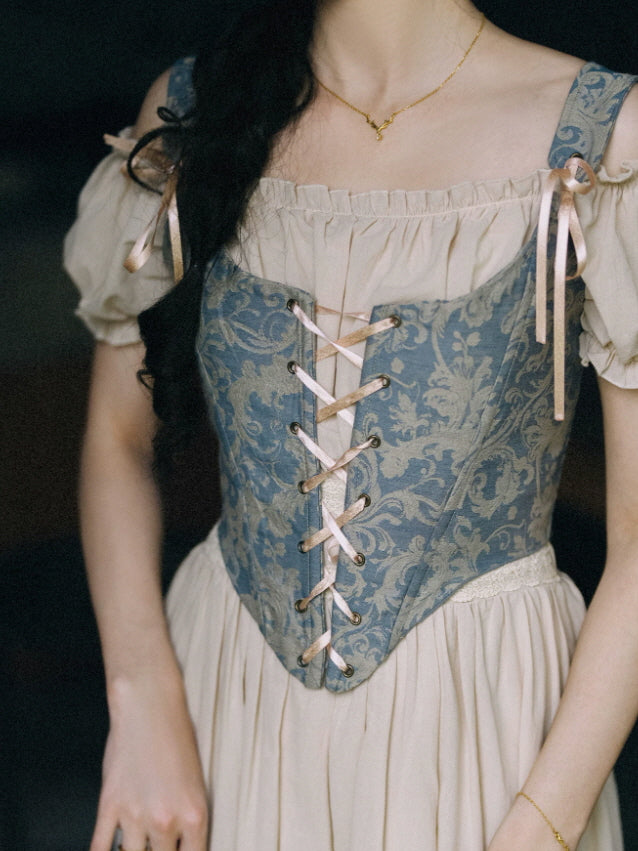 Close up of blue vintage corset dress with floral pattern bodice, lace up front and cream puff sleeve details