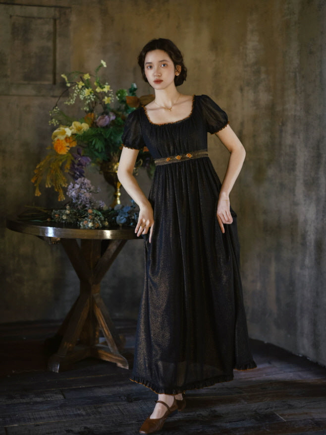 Long black vintage dress with square neckline, short puff sleeves and flowing skirt in a dark cottagecore interior
