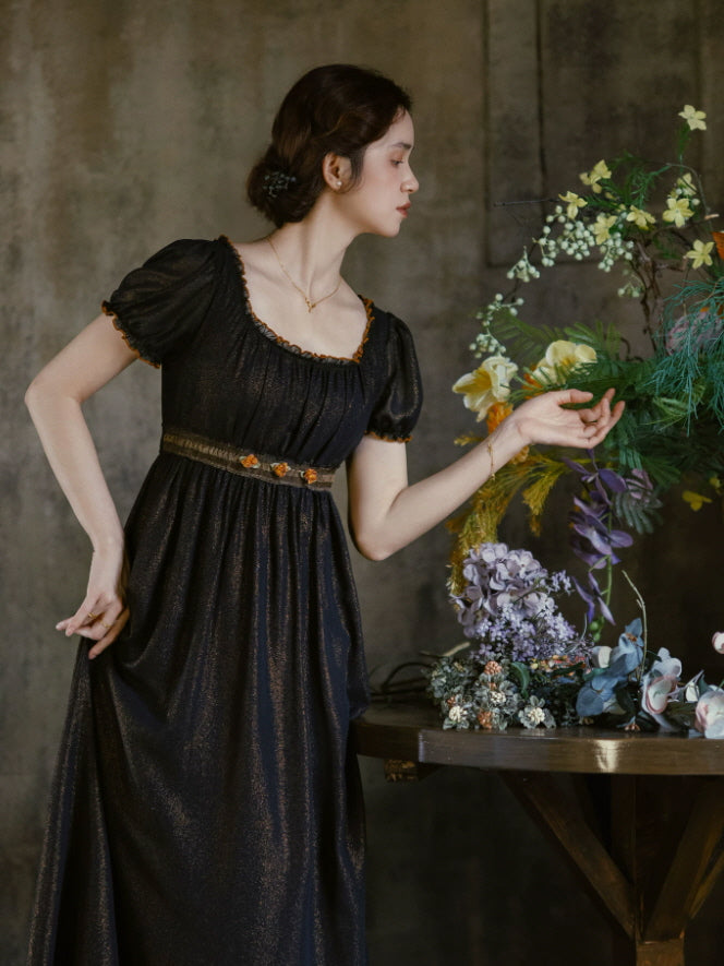 Romantic black cottagecore dress with gathered bodice, short puff sleeves and subtle orange floral embroidery at the waist