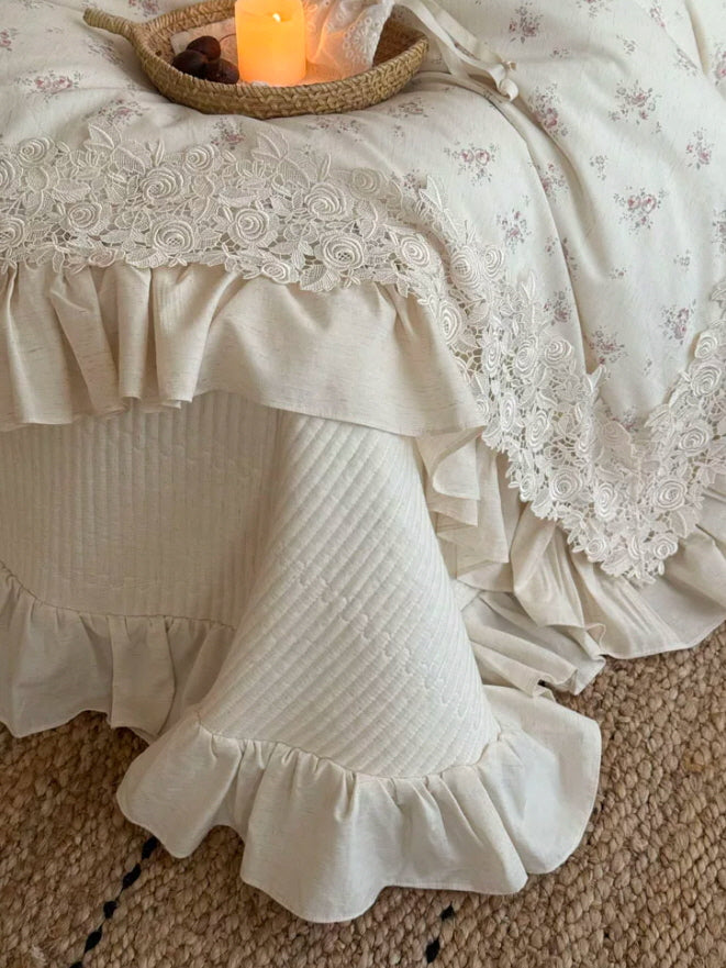 Vintage floral bedding with delicate rose lace edging, layered ruffles, and cream pillow shams for a dreamy cottagecore interior