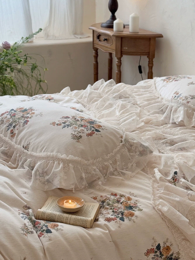 Shabby chic bedding with floral bouquet print, layered sheer lace ruffles, and soft romantic detailing for a dreamy bedroom