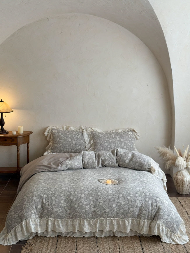 Soft gray embroidered bedding with layered ivory ruffles and vintage floral details