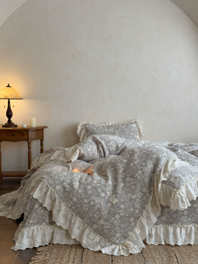 Warm gray floral bedding with ivory ruffle trim styled in a vintage-inspired bedroom