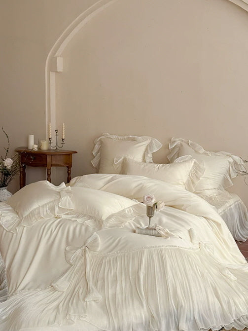 Cream ruffled bedding with oversized bow details and soft layered pillow shams