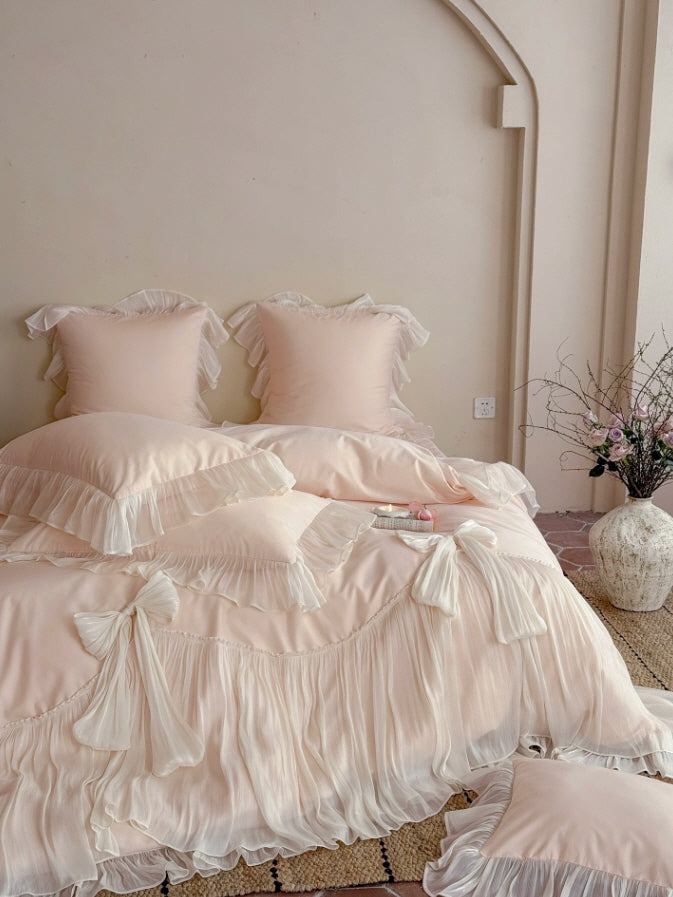 Soft pink princesscore bedding with oversized bow accents and layered ruffle pillow shams