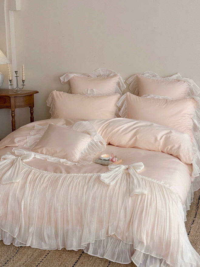 Soft pink ruffled bedding set with graceful ivory trim and elegant bow embellishments