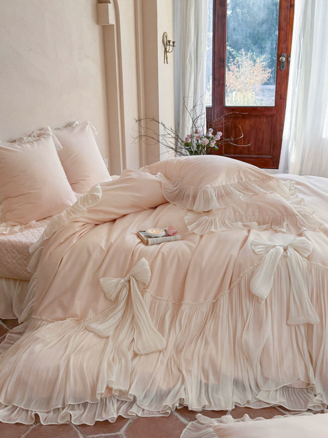 Vintage-inspired blush bedding with flowing ruffle edges and delicate bow accents