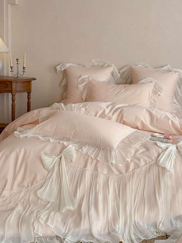 Pale pink ruffle bedding with flowing skirt trim and feminine bow accents