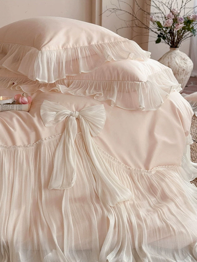 Close-up of pink and ivory bow bedding with layered ruffles and flowing pleated fabric