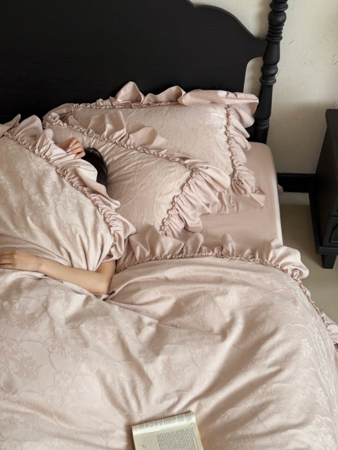 Soft blush pink bedding with romantic floral pattern and ruffled border details