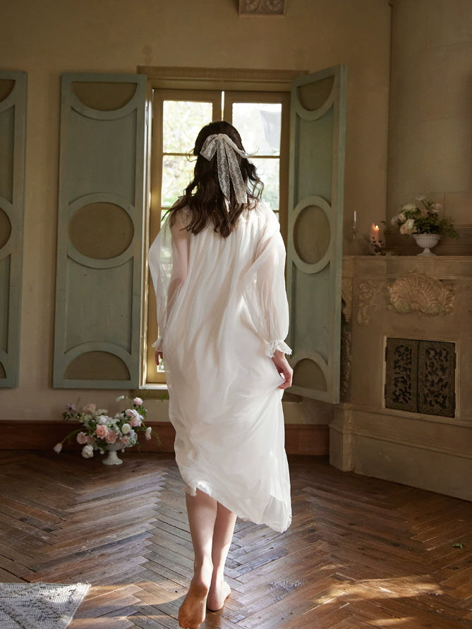Back view of flowing white nightgown with sheer long sleeves and delicate lace trim