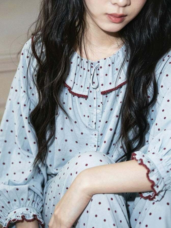 Close up of light blue polka dot cotton pajama top with burgundy trim, tie neckline and ruffled cuffs