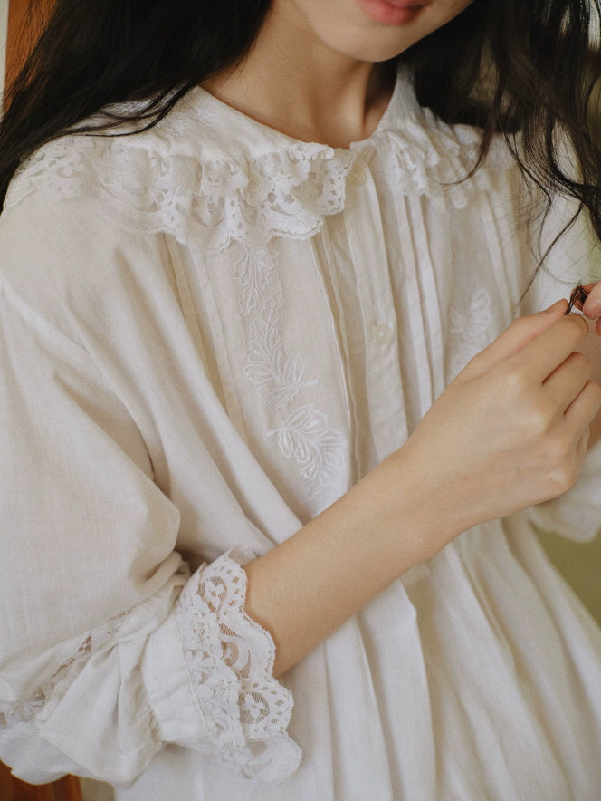 Close up of white cotton nightgown featuring floral embroidery, lace collar and ruffled cuffs