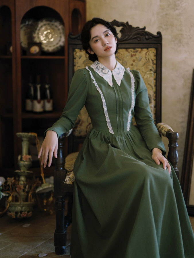Close-up of green cottagecore dress featuring white lace collar, cameo brooch and delicate vertical lace trim