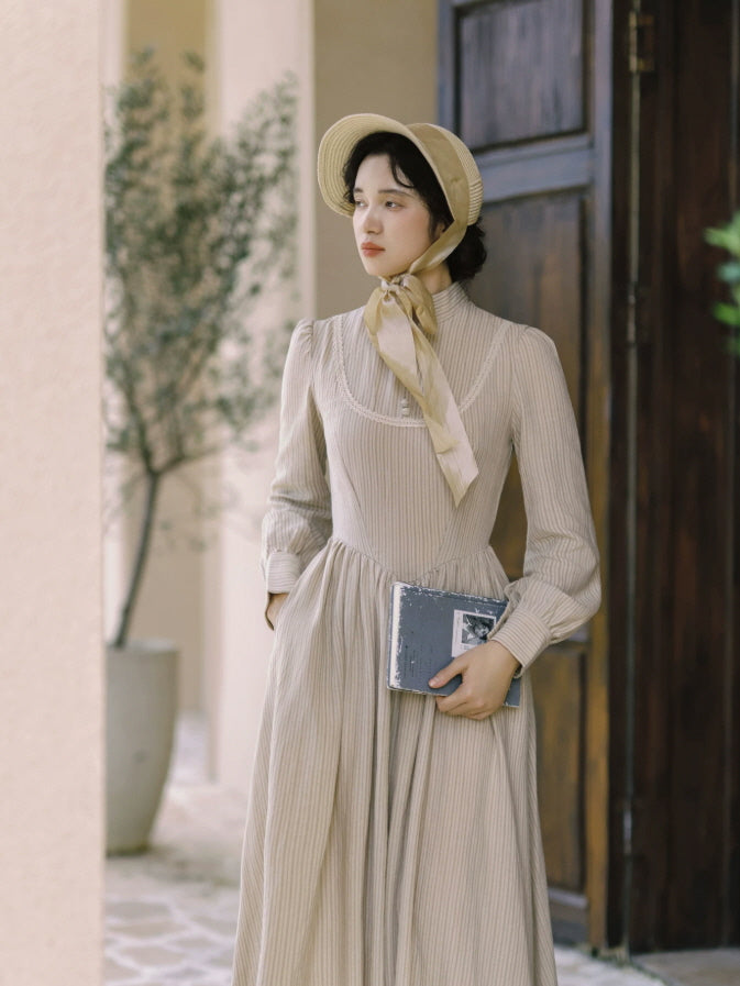 Beige striped vintage maxi dress with high neckline, lace trim and long sleeves in a romantic antique interior