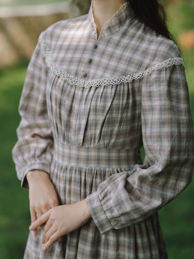 Close-up of vintage plaid dress featuring high collar, decorative buttons and delicate white lace trim