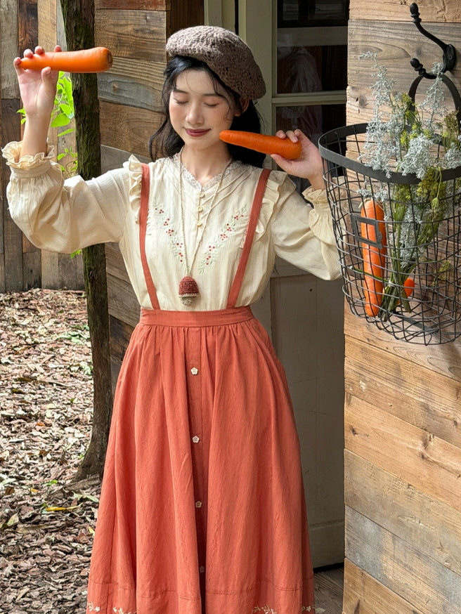 Vintage-inspired cream blouse with floral embroidery, ruffle details and terracotta suspender skirt