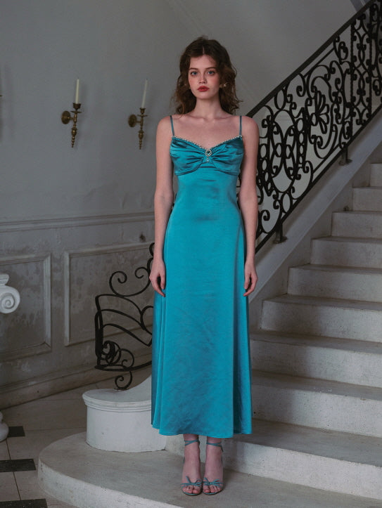 A woman gracefully poses on a grand staircase, wearing a flowing turquoise satin dress with a delicate ruched bodice and floral hair accessory — vintage evening fashion, princess-inspired aesthetic, dreamy fairytale look.