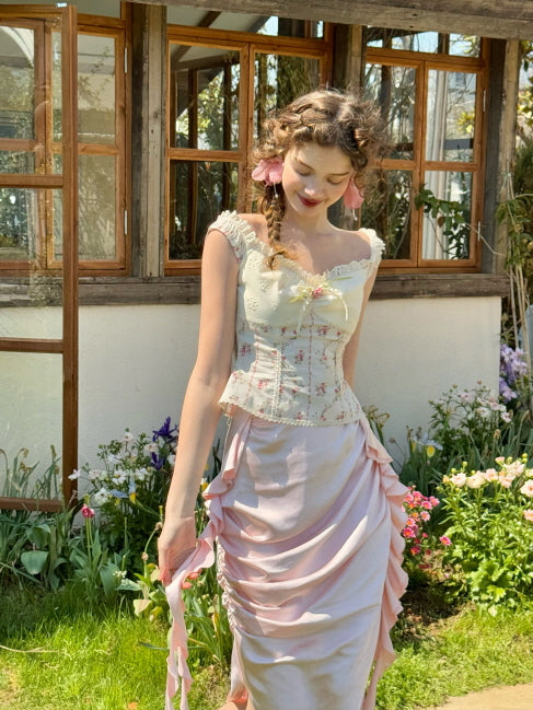 Romantic pastel pink ruched satin skirt with ribbon details, styled with a floral off-shoulder corset top in a spring flower garden – fairytale vintage outfit for women