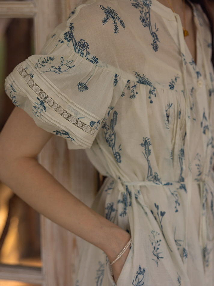 Close-up view of a floral print dress with delicate lace trim on the puff sleeves, showcasing intricate blue botanical patterns on a soft, lightweight fabric