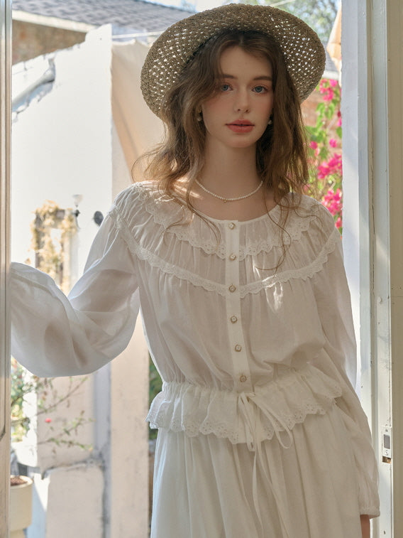 A young woman in a white cottagecore blouse and skirt with lace details, standing by an open door under sunlight, wearing a straw hat and pearl necklace, showcasing a retro and romantic outfit