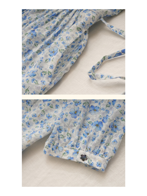 Close-up of the blue floral print fabric showing delicate tie details at the waist and a floral-shaped button at the cuff, emphasizing vintage charm and feminine elegance.