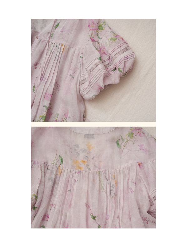 A close-up view of a pastel lilac floral dress with delicate puff sleeves adorned with lace detailing. The dress fabric is lightweight and slightly sheer, featuring a romantic flower pattern in soft pink, green, and yellow hues.
