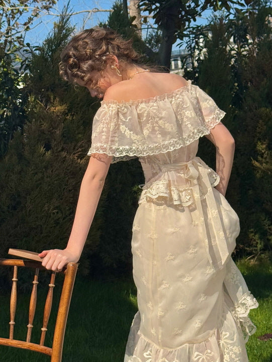 Back view of ivory embroidered corset dress with lace ruffle collar and ribbon waist tie, styled in a sunlit garden – romantic vintage aesthetic for women