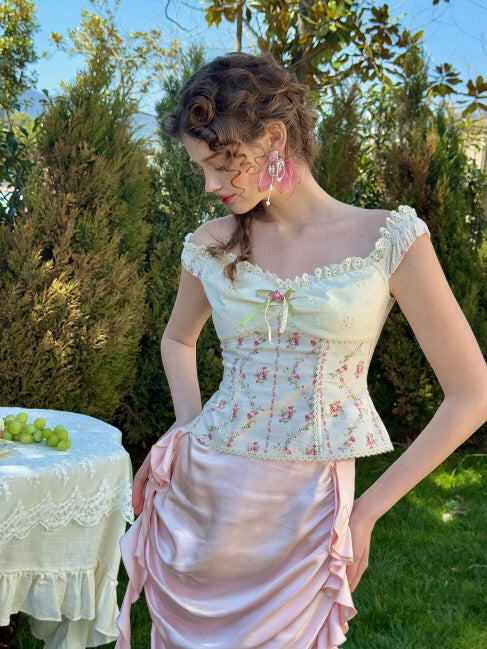 Romantic pastel pink ruched satin skirt paired with a floral embroidered off-shoulder corset top, styled in a spring garden – vintage fairytale aesthetic outfit for women