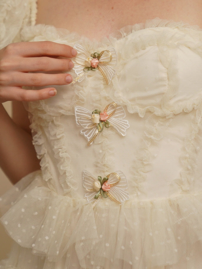 Close-up of delicate floral ribbon bows on a soft ivory bodice, highlighting the romantic vintage details of this fairycore-style dress.