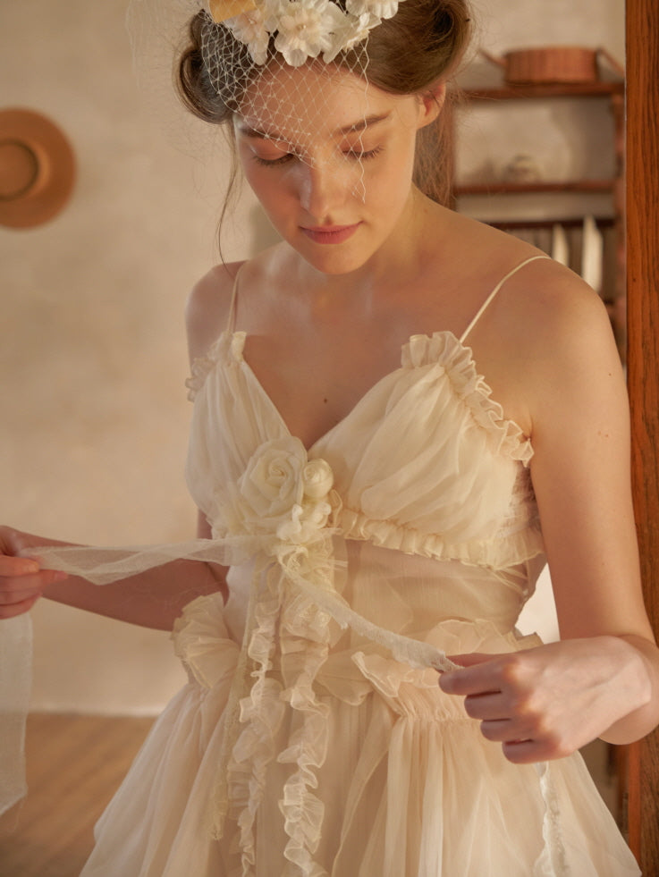 Close-up of a romantic ivory dress with rosette and lace tie accents, highlighting its fairycore charm and vintage-inspired softness.