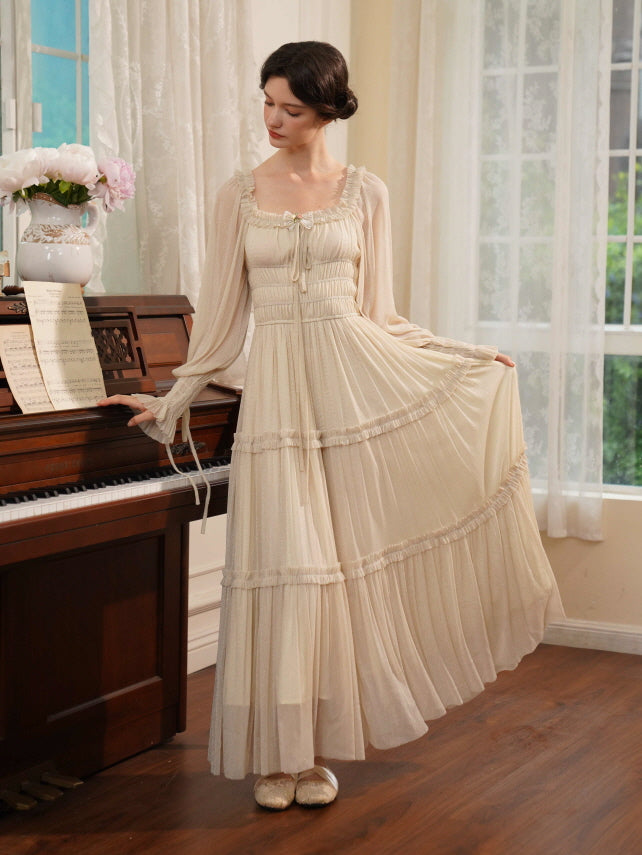 A model stands beside a piano in a cream pleated gown with delicate frills and long sleeves, evoking a timeless princesscore aesthetic.