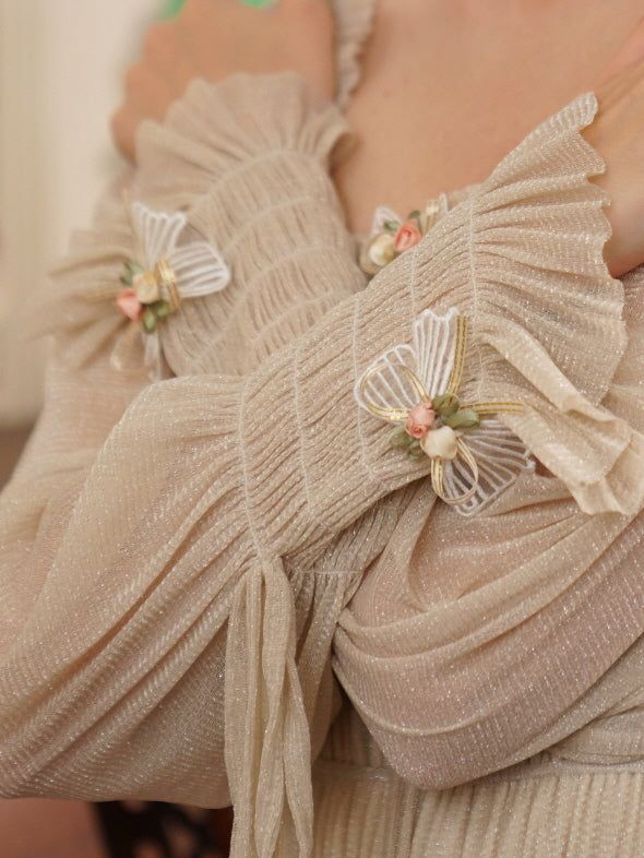 Close-up of pleated cream chiffon sleeves with delicate floral ribbon appliqués, highlighting the vintage charm of the dress.