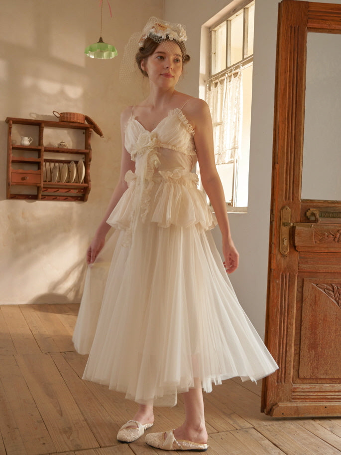 Model in a dreamy cream tulle dress with floral ribbon detail, styled with a vintage veil headpiece in a fairytale-inspired setting