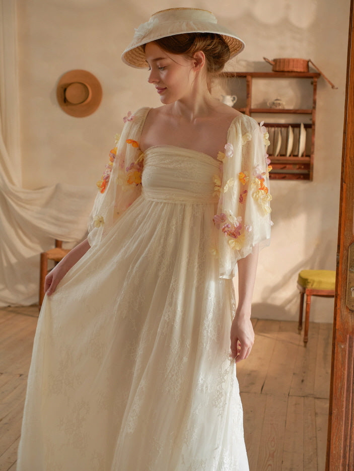 The model stands gracefully in a soft cream strapless lace dress with 3D floral appliqué sleeves, evoking a dreamy fairycore charm.