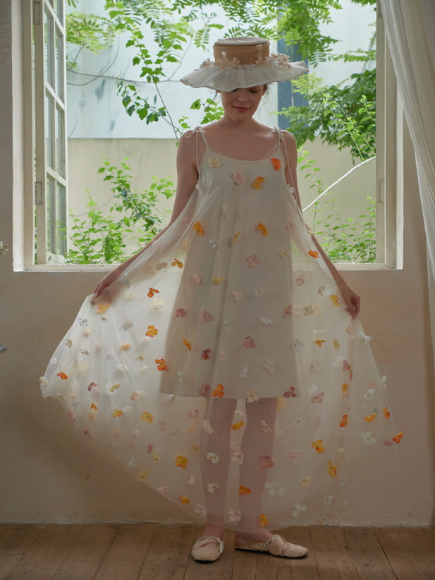 A model gracefully spreads the sheer floral overlay of a romantic embroidered mesh dress, radiating soft fairycore charm in a vintage sunlit room.