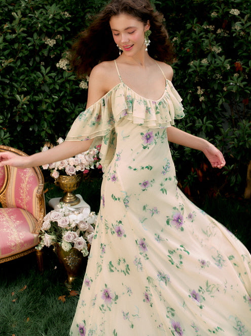 The model twirls in a flowing off-shoulder floral dress with ruffle detail, surrounded by roses in a vintage garden, evoking a fairycore summer vibe.